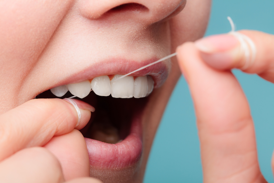 Closeup of a woman flossing her teeth with string floss