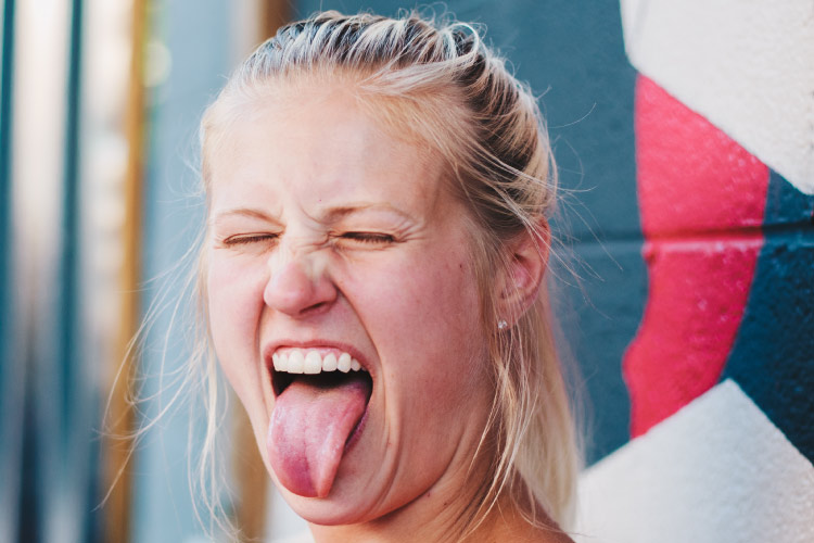 Blonde woman sticks her tongue out while closing her eyes