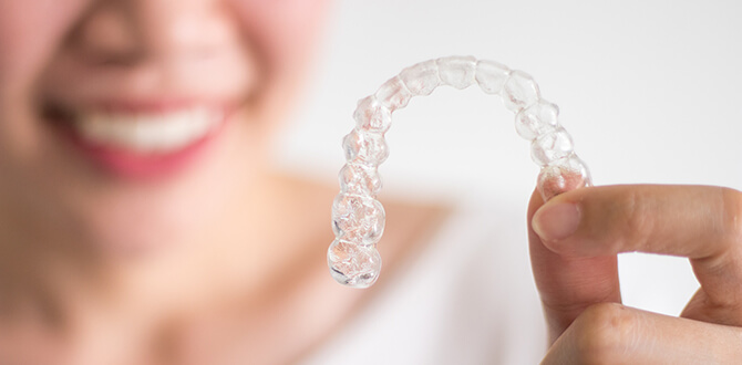 closeup of a person holding up a clear aligner