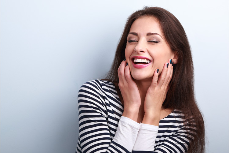 Brunette woman with striped shirt smiles after successfully flossing her tight teeth