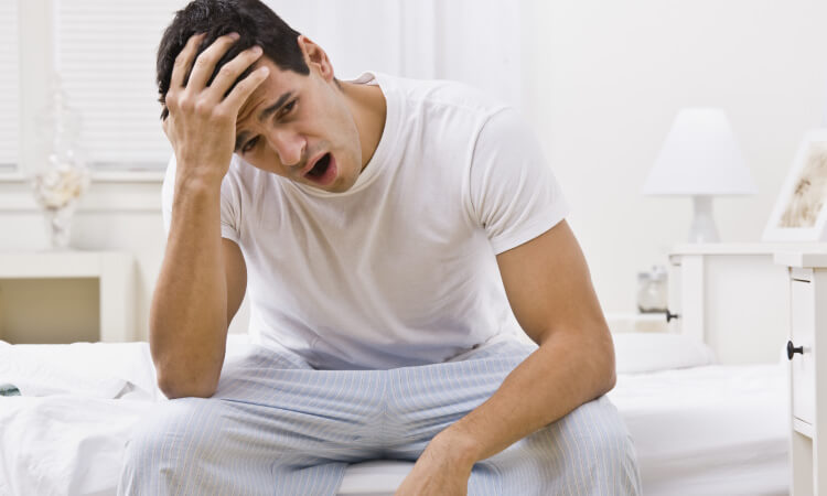 Man with sleep apnea yawns after waking up with a headache and sleepiness