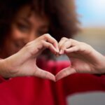 show smile some love, woman holding up heart sign with hands