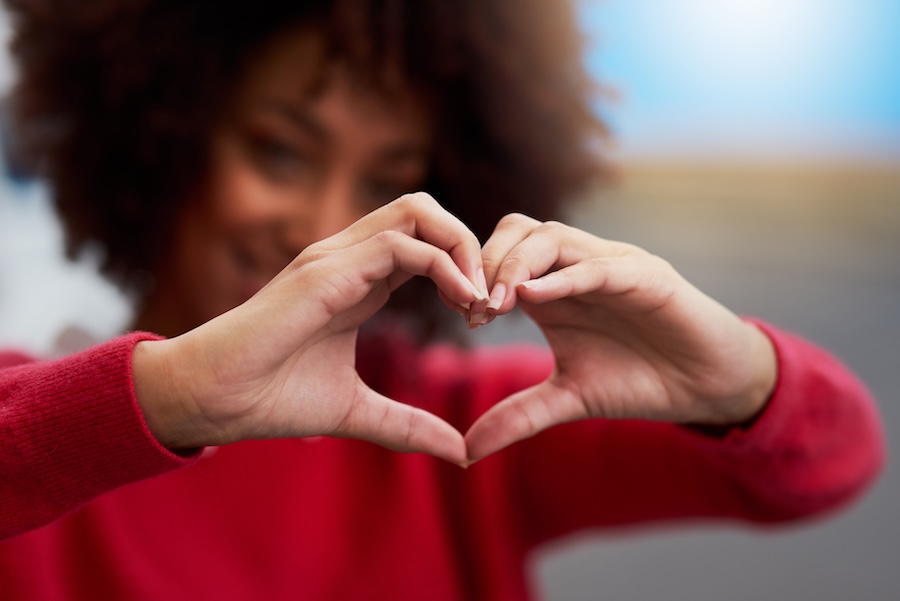 show smile some love, woman holding up heart sign with hands